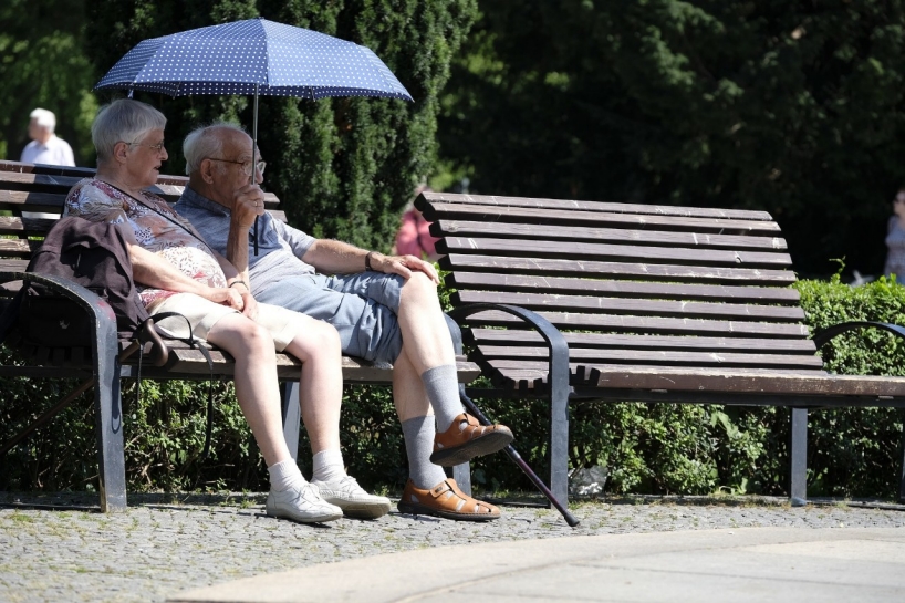 Ältere Personen im Park unter Sonnenschirm